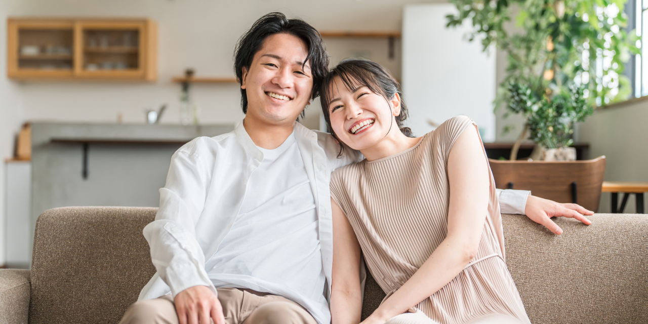 ソファで寄り添って笑う夫婦